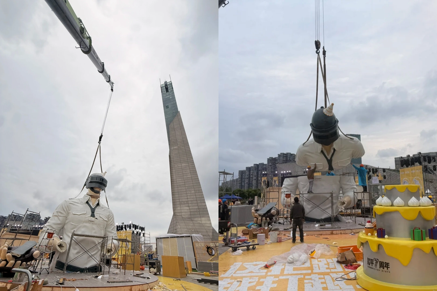 The upper body structure of the large outdoor art installation is lifted by a crane, positioned above a giant yellow celebration cake-shaped base.