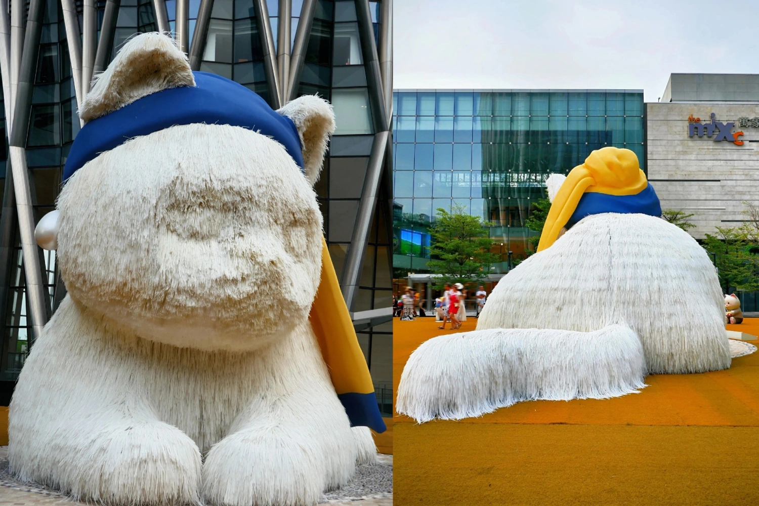 Close-up side view of a giant white plush cat wearing a blue and yellow scarf, and its massive back view on the plaza, with a modern shopping mall building in the background.