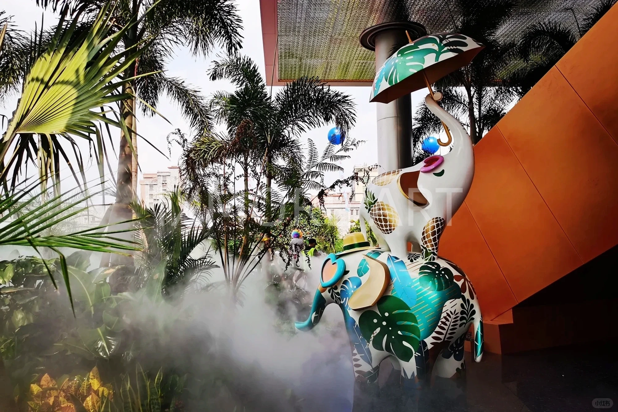 Long shot of Tropical Baby Elephant IP sculpture outside mall, mist spray dynamic device customized by professional art factory, overall finished effect of large outdoor public art installation(3)