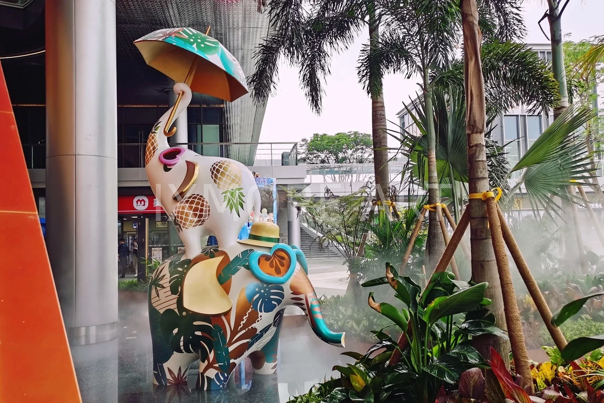 Long shot of Tropical Baby Elephant IP sculpture outside mall, mist spray dynamic device customized by professional art factory, overall finished effect of large outdoor public art installation(4)
