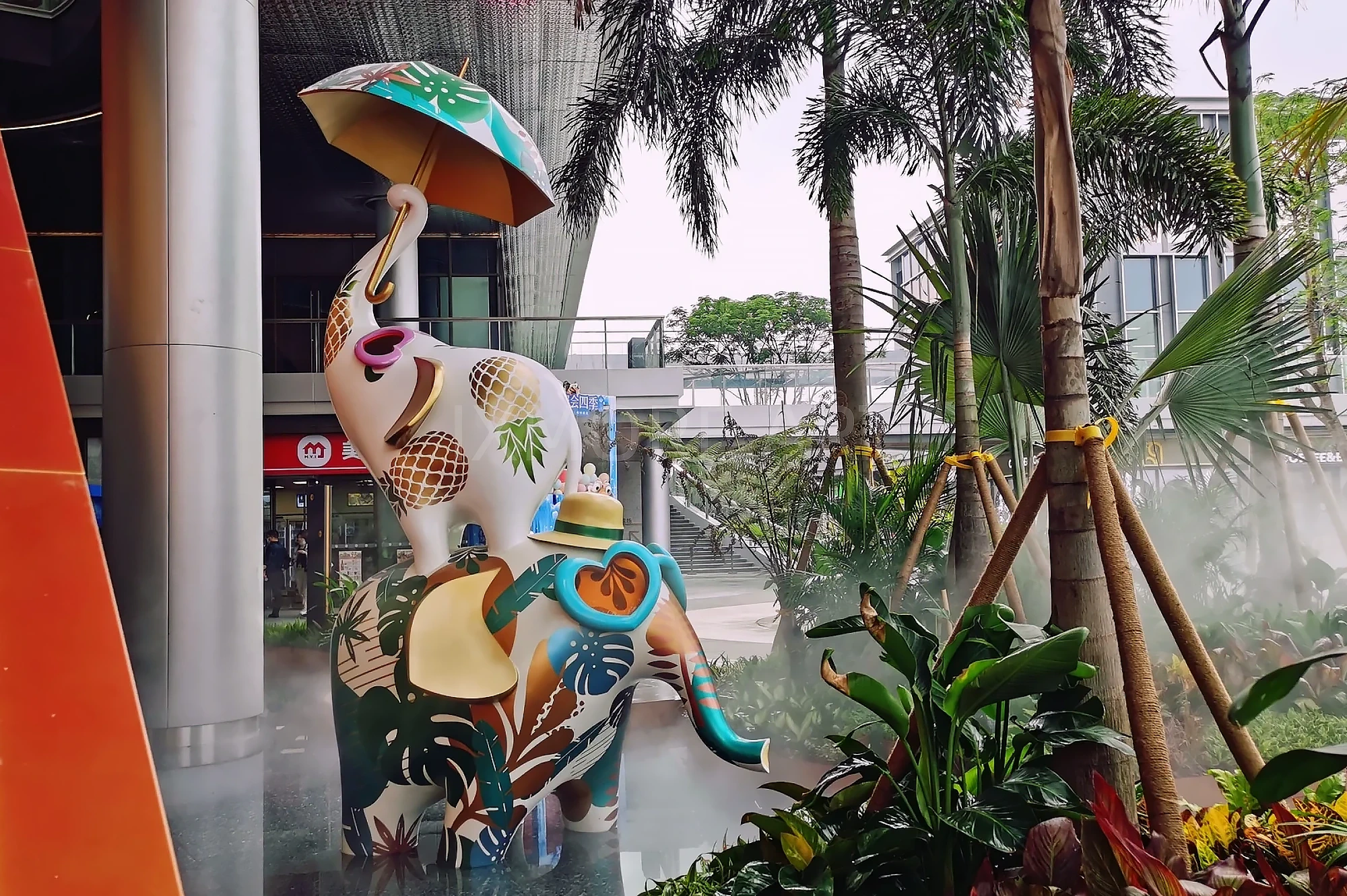 Long shot of Tropical Baby Elephant IP sculpture outside mall, mist spray dynamic device customized by professional art factory, overall finished effect of large outdoor public art installation(4)